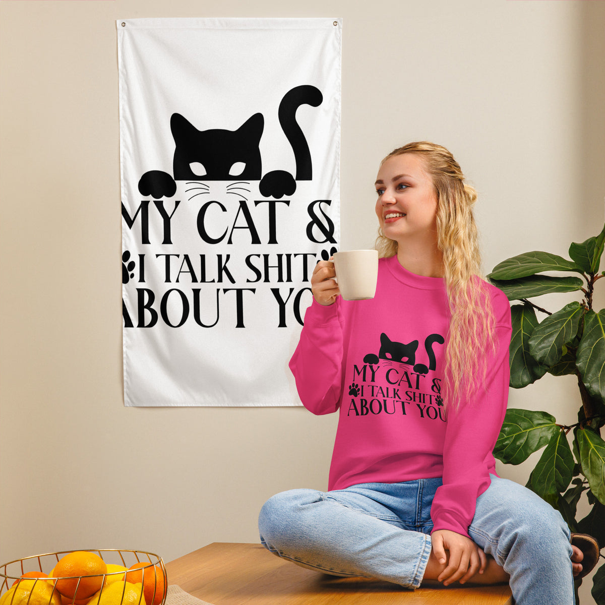 Model wearing a sweatshirt in Heliconia with a black cat graphic and My Cat and I Talk Shit About You lettering
